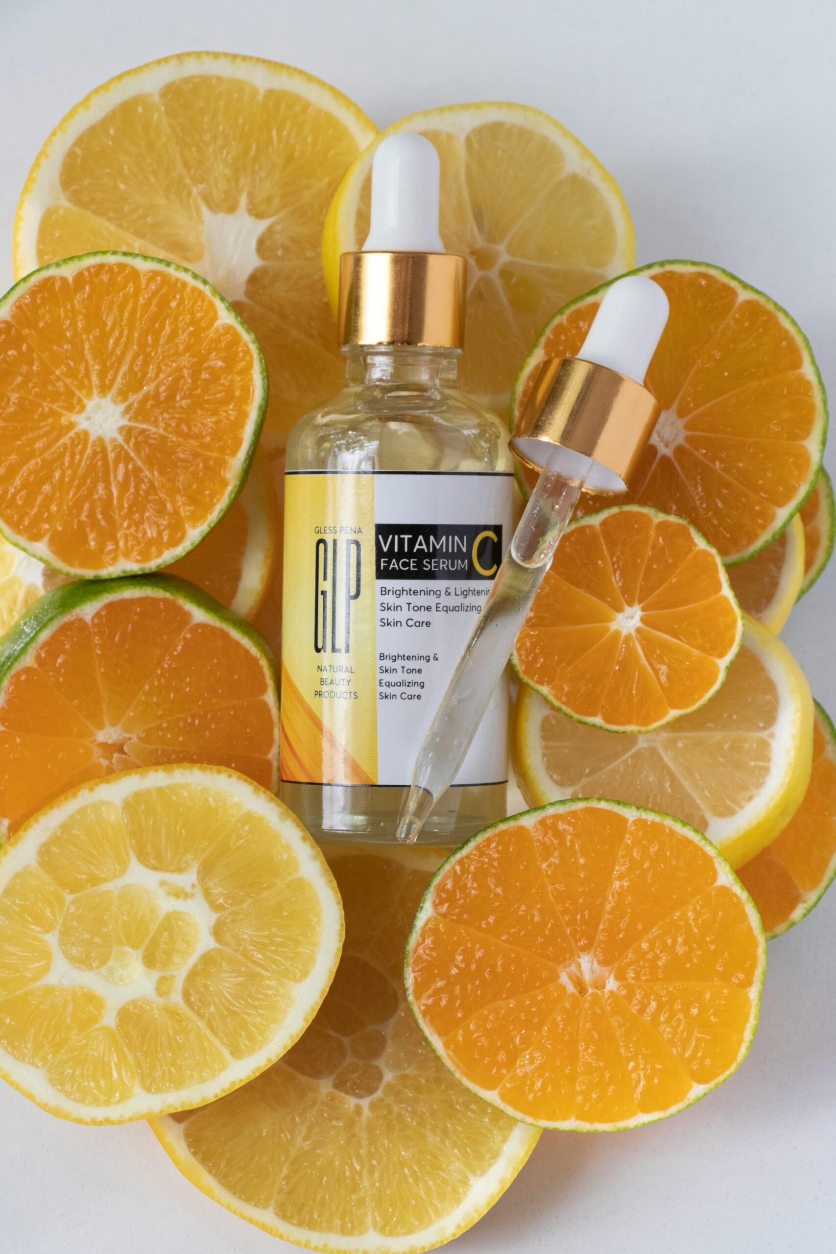 Brightening serum surrounded by fresh orange and lemon slices for skincare boost.